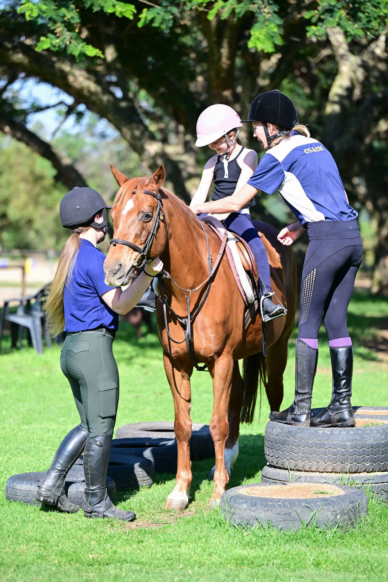 Young rider being helped onto a horse by coaches at Sun Valley Stables, Kyalami